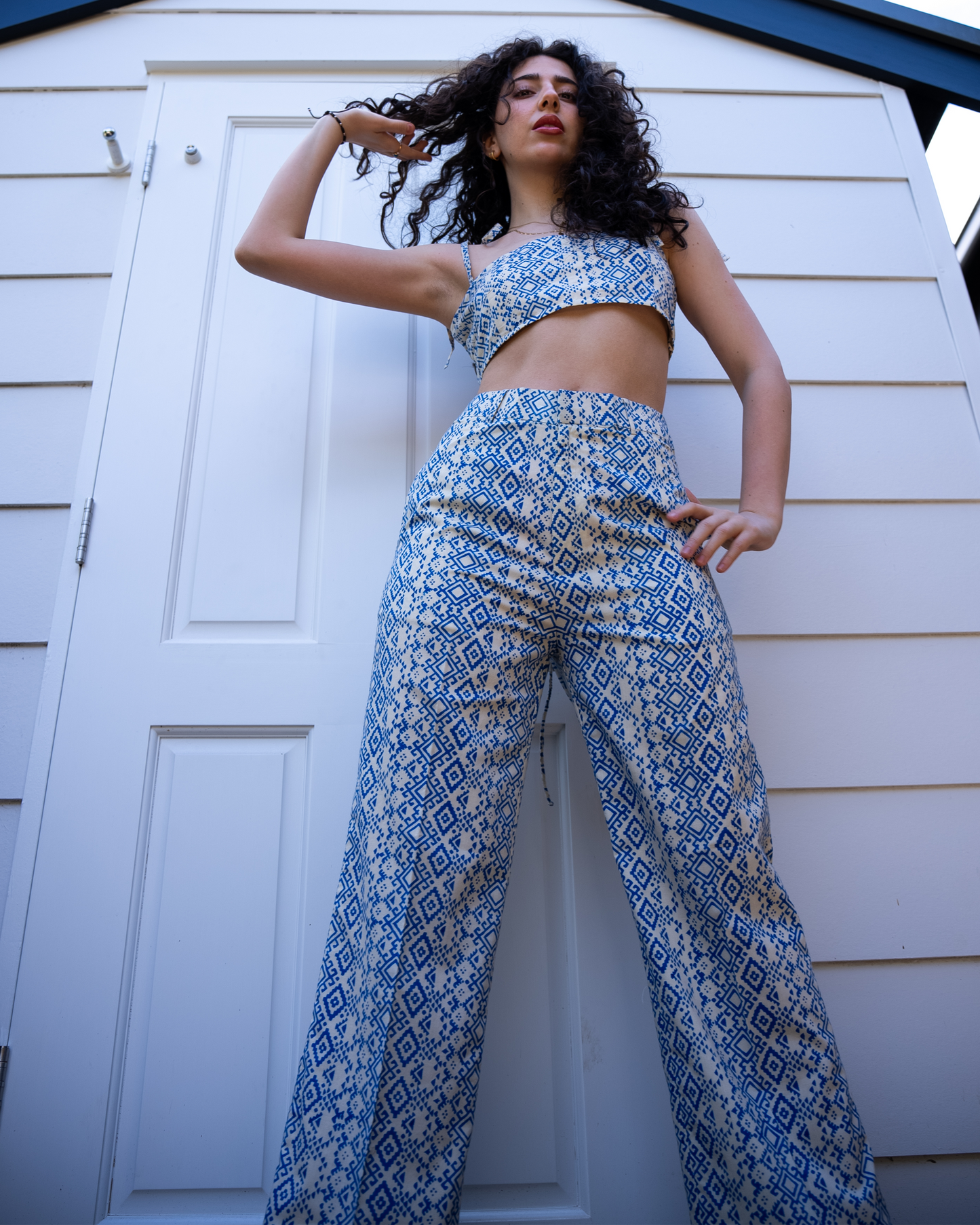 Low-angle full outfit shot of Aroa crop top and Marisa wide-leg pants, blue geometric print two-piece set