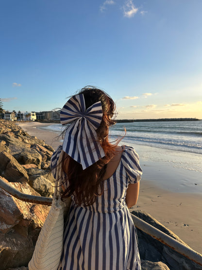 Woman in a striped dress and sun hat on a beach