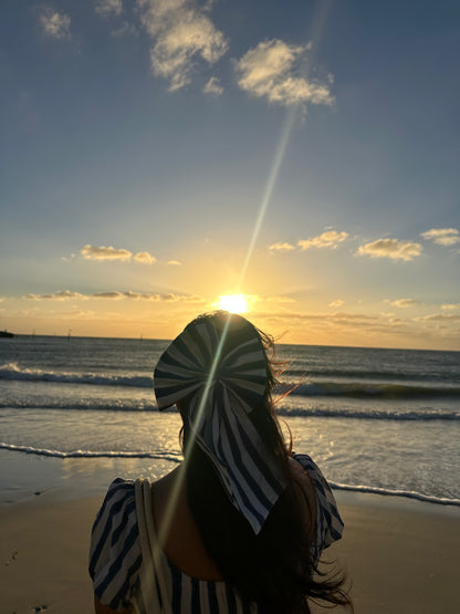 Person standing on a beach at sunset with sun lens flare