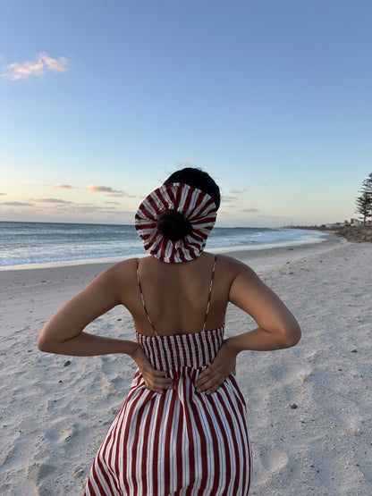 Person wearing a red and white striped dress and headscarf on a beach.