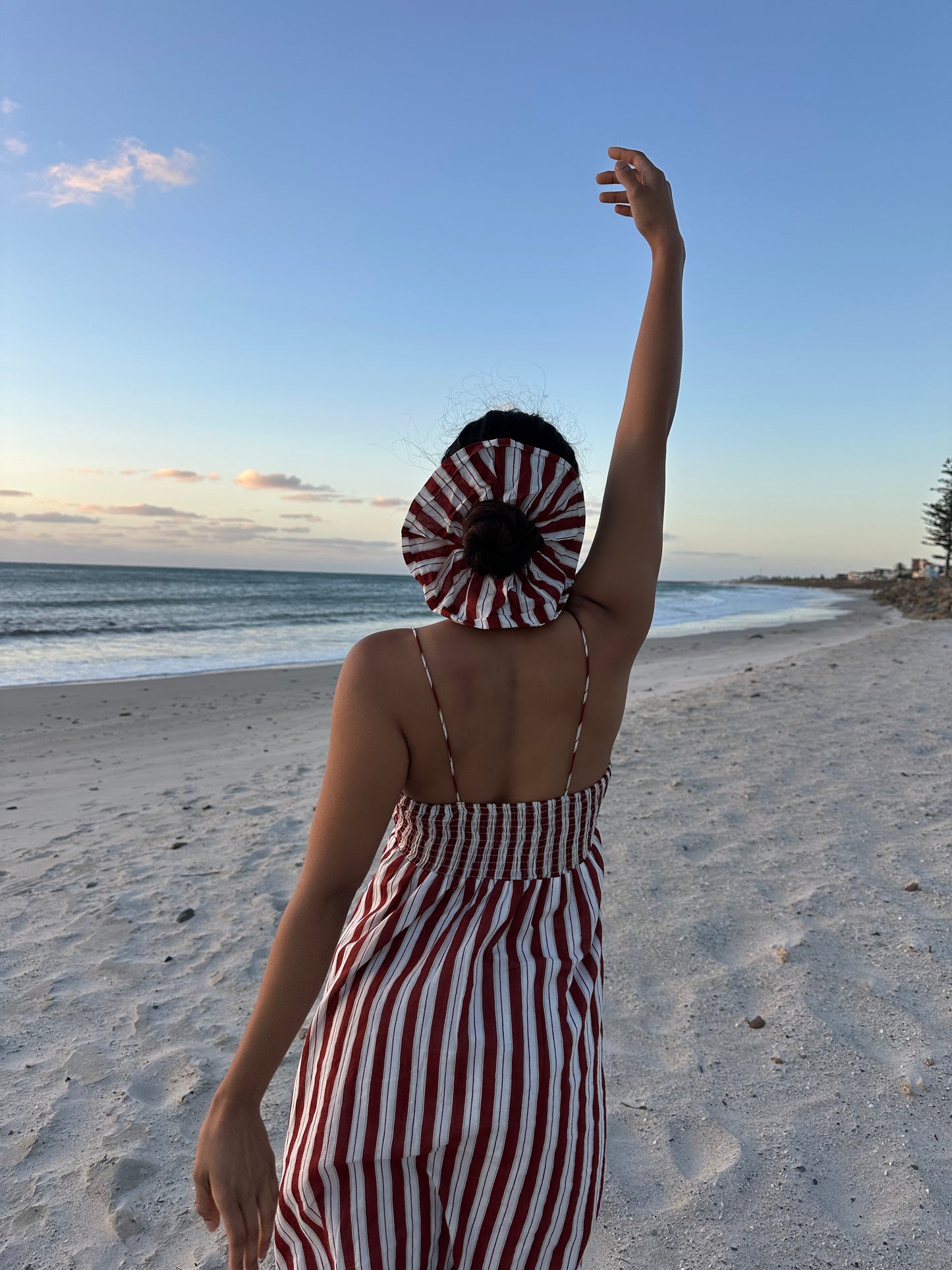 Woman in a striped dress standing on a beach with ocean view