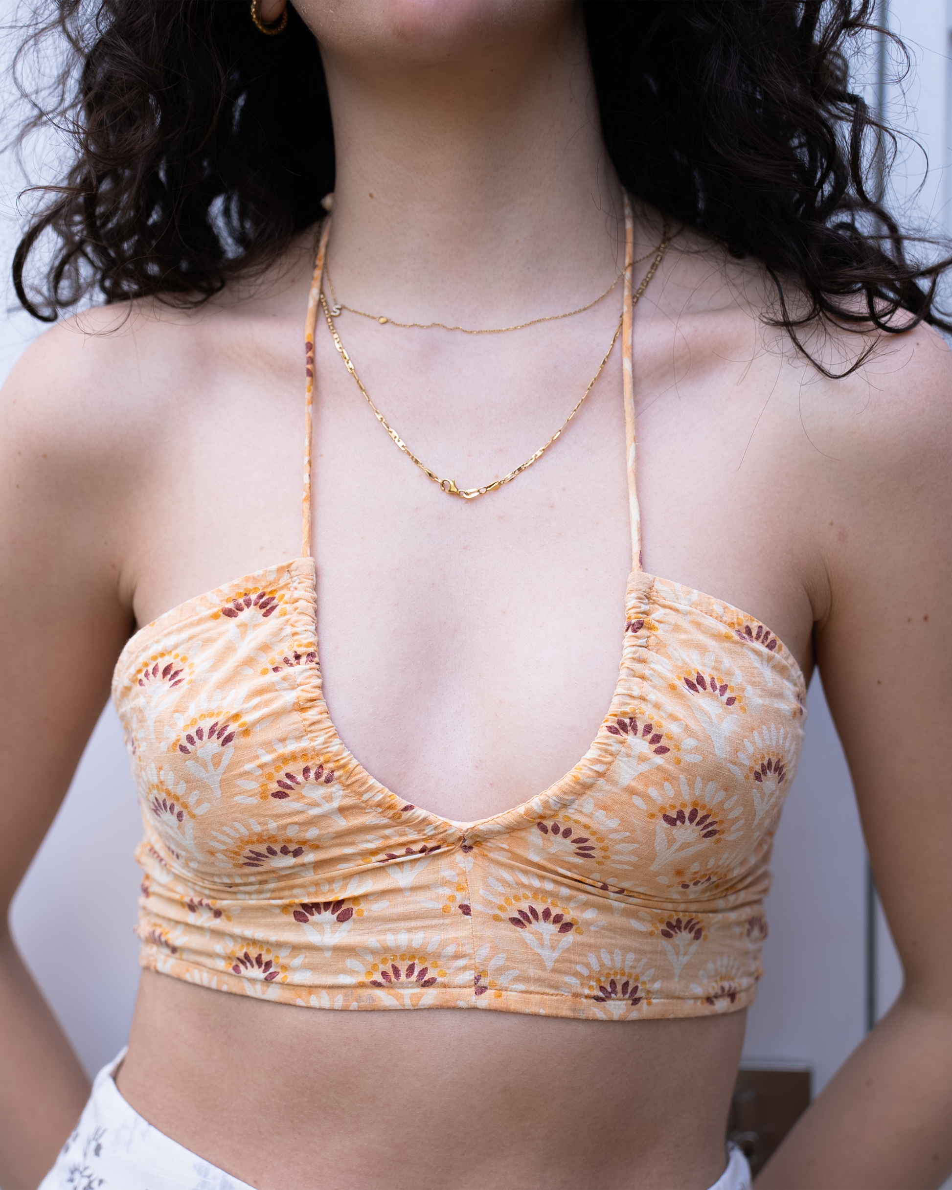 Close-up of Jaipur halter crop top neckline and hand-block print detail in warm orange tones 