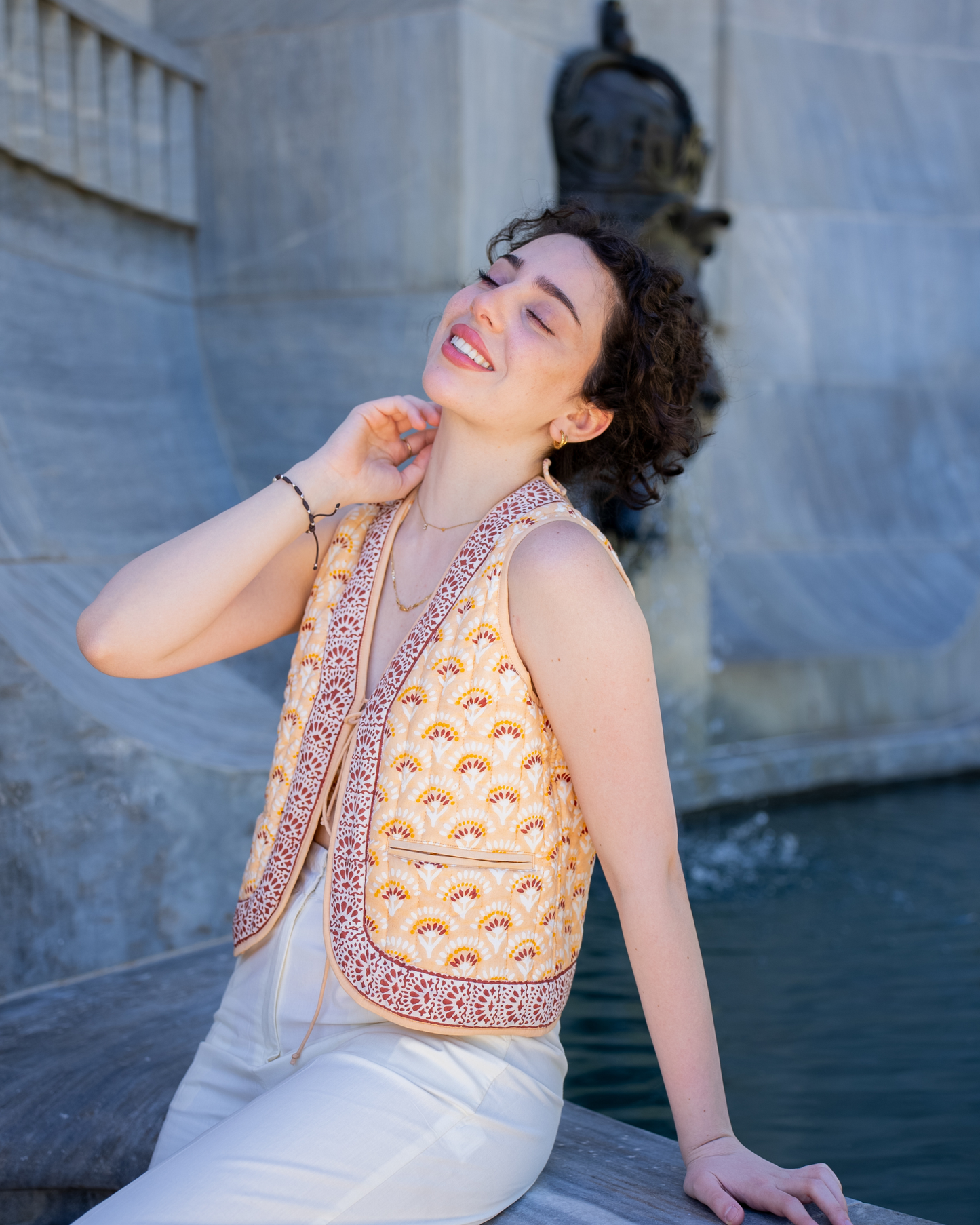 Boho Bay Half Sleeve Quilted Jacket – lifestyle front view on model by fountain, showing quilted cotton print and contrast border trim