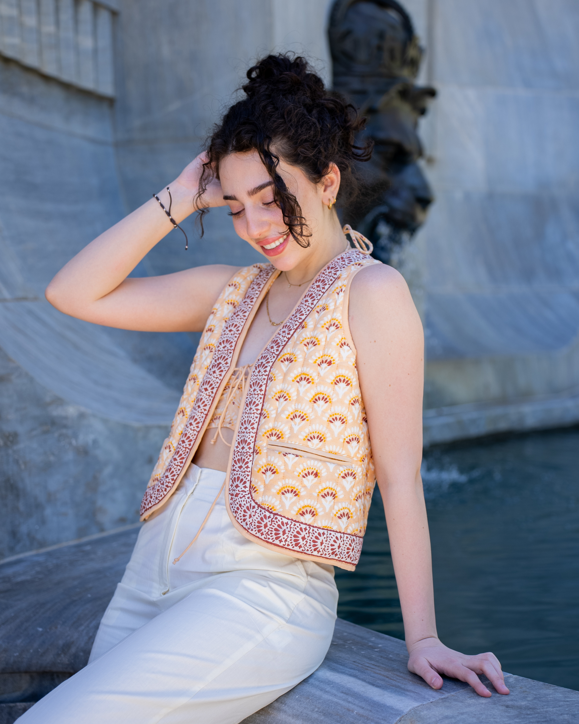 Boho Bay Half Sleeve Quilted Jacket – lifestyle front view on model by fountain, showing quilted cotton print and contrast border trim